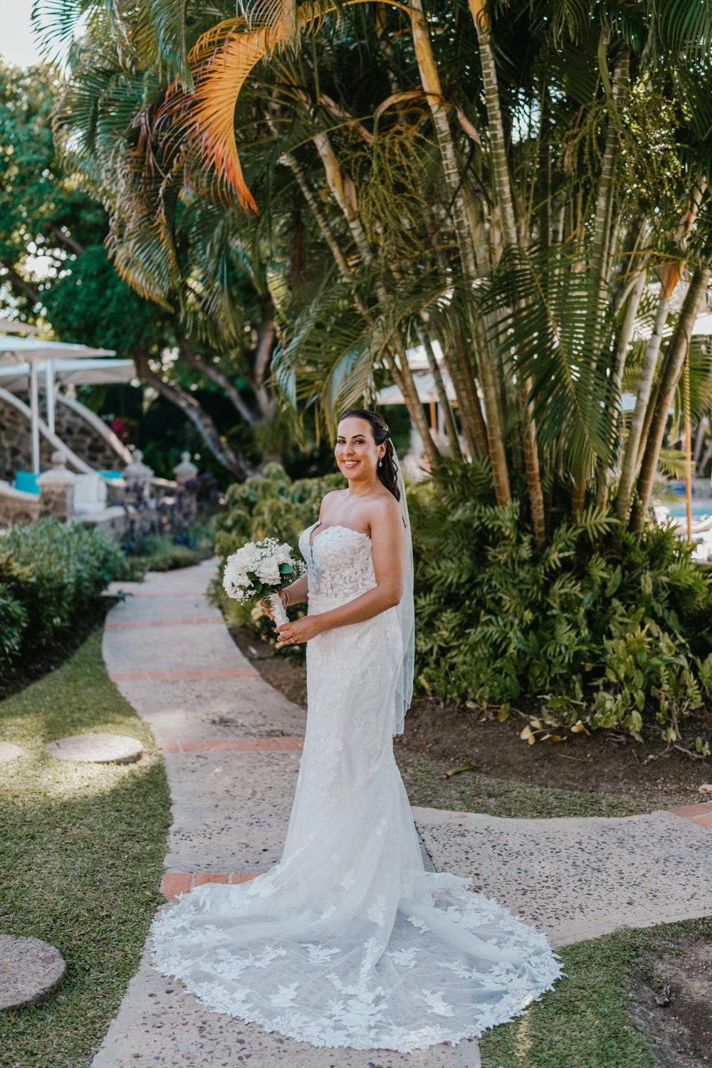 bride poses in front of palm trees in saint lucia at stolentime by rendezvous wedding venue