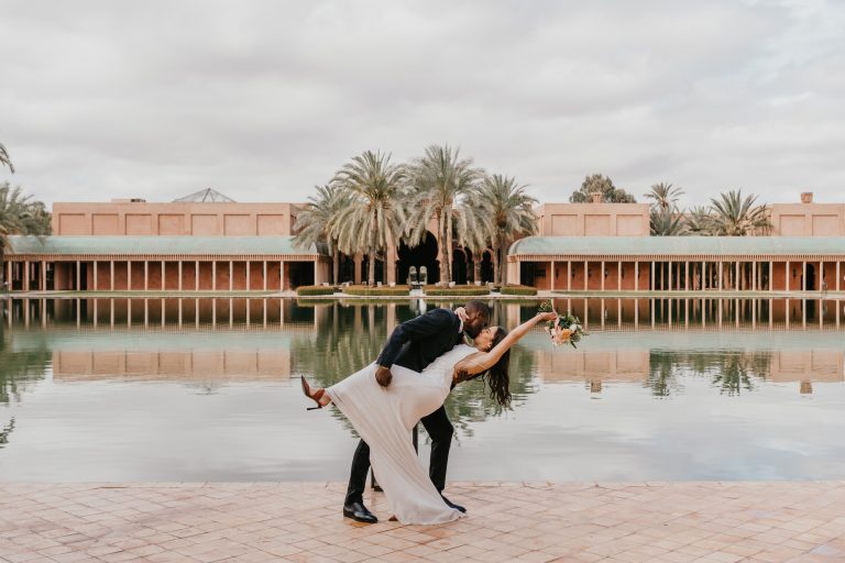 bride and groom dip-kiss in front of the pool at amanjena marrakech wedding venue