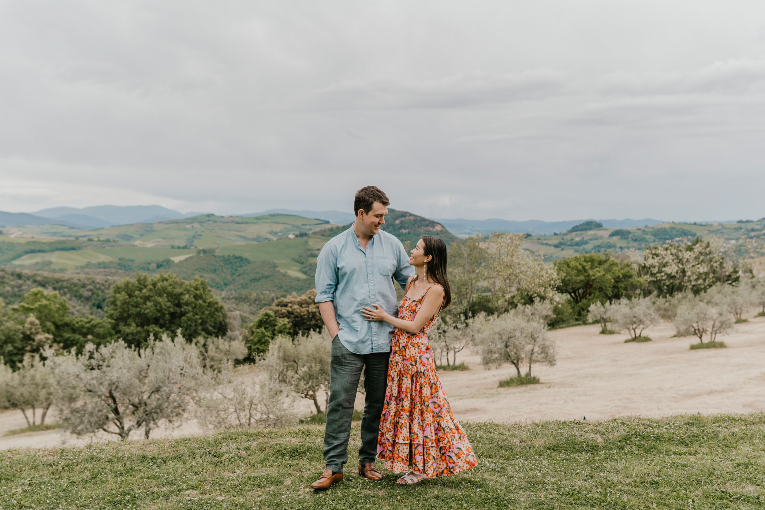 couple stood with the rolling tuscan hills as the backdrop on their pisa couple shoot at villa di ulignano