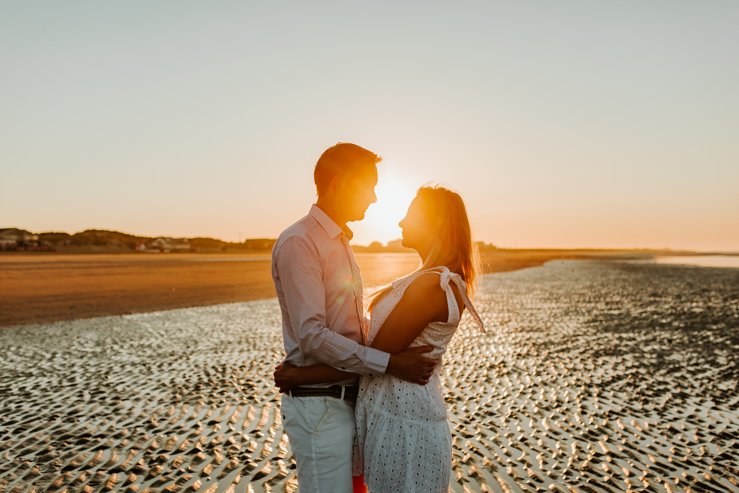 couple embrace at sunrise on a sandy beach