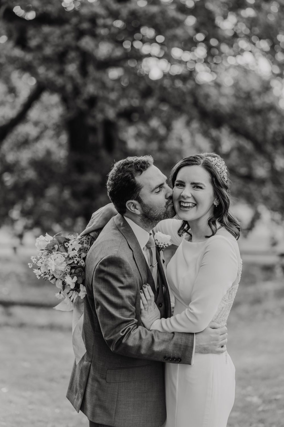 black and white photo of groom kissing bride on the cheek at london wedding