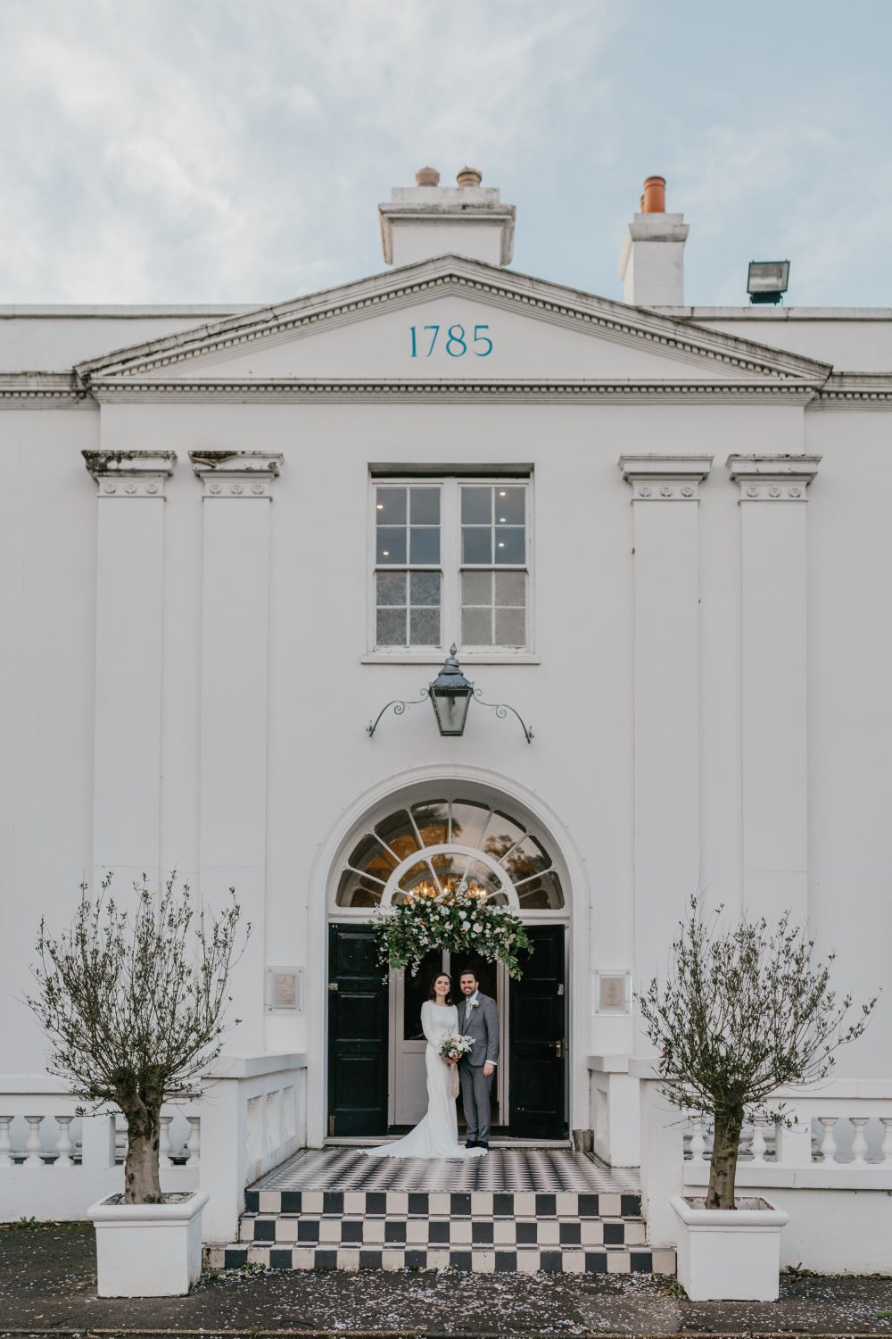 bride and groom stand at the door at belair house wedding venue in london