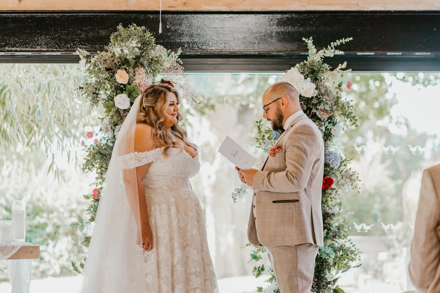 groom reads his vows as bride looks at him at indoor ceremony at chapel house estate in kent