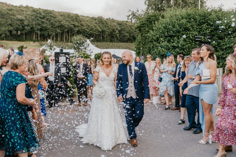 bride and groom walk through confetti line at The BarnYard wedding venue in kent