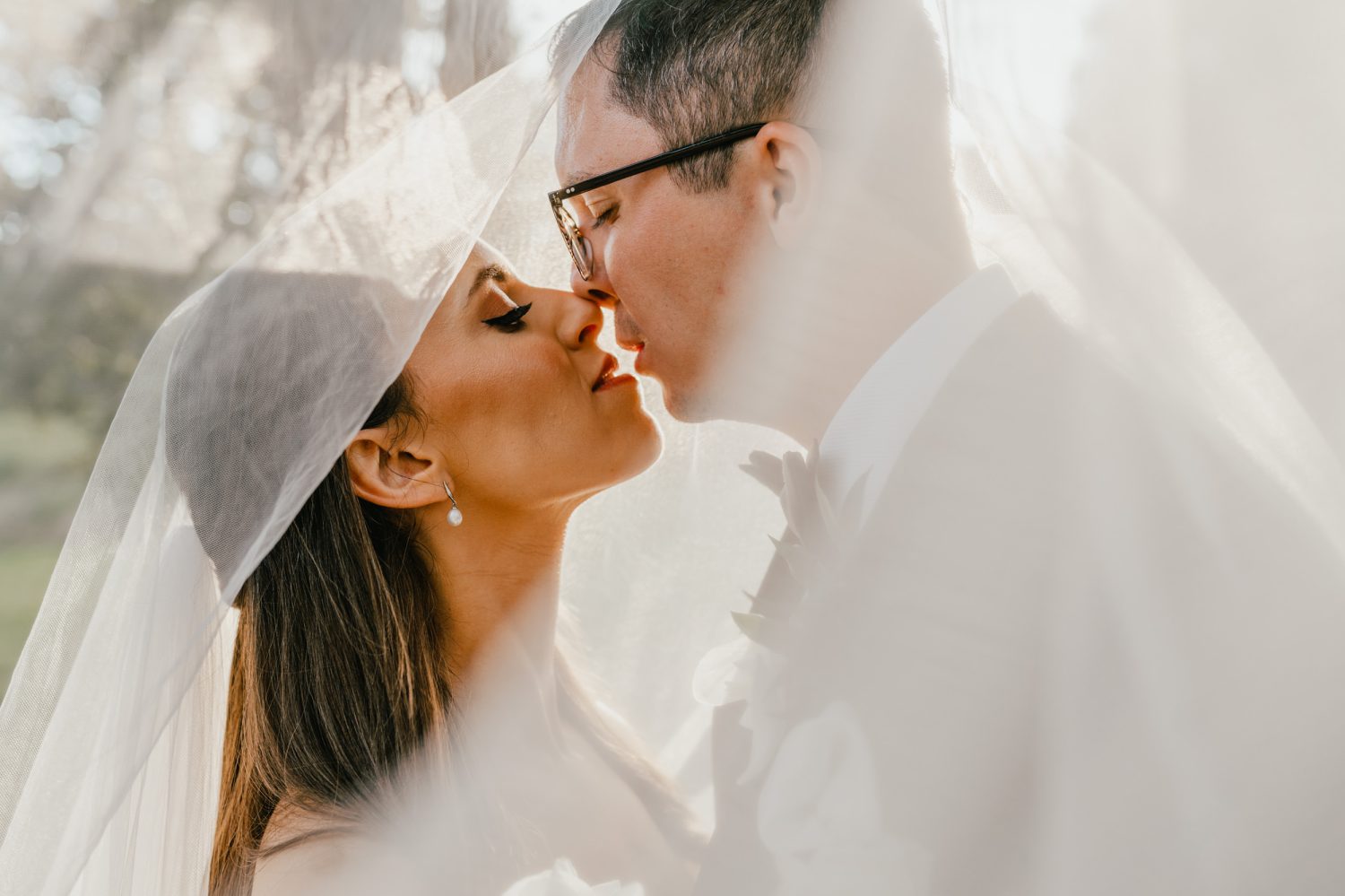 couple embrace under bride's veil during sunset couple portraits at the beacon wedding venue in kent
