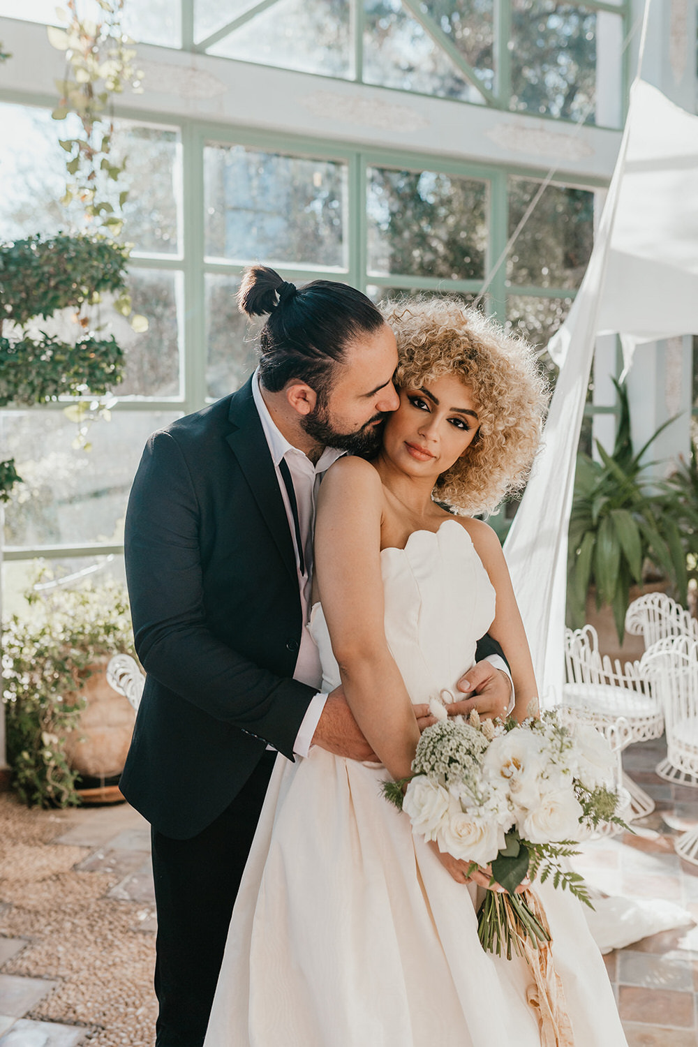 bride and groom embrace in golden hour light in the greenhouse at beldi country club wedding venue in marrakech