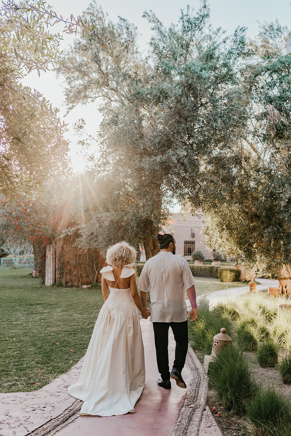 bride and groom walk through the gardens in golden hour light at beldi country club wedding venue in marrakech