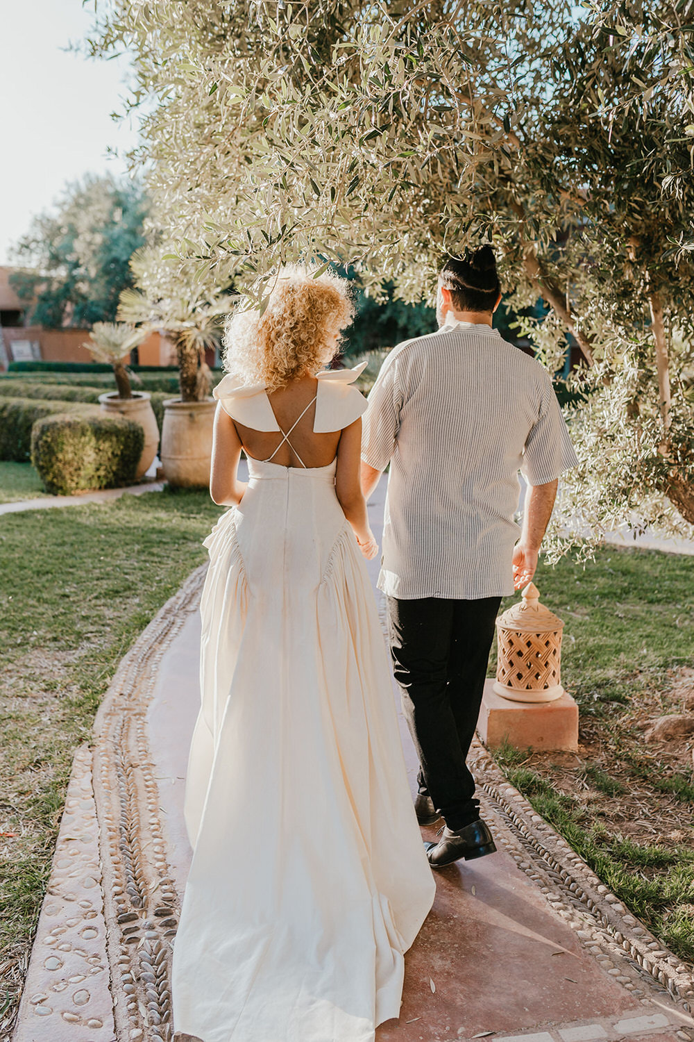 bride and groom walk through the gardens in golden hour light at beldi country club wedding venue in marrakech