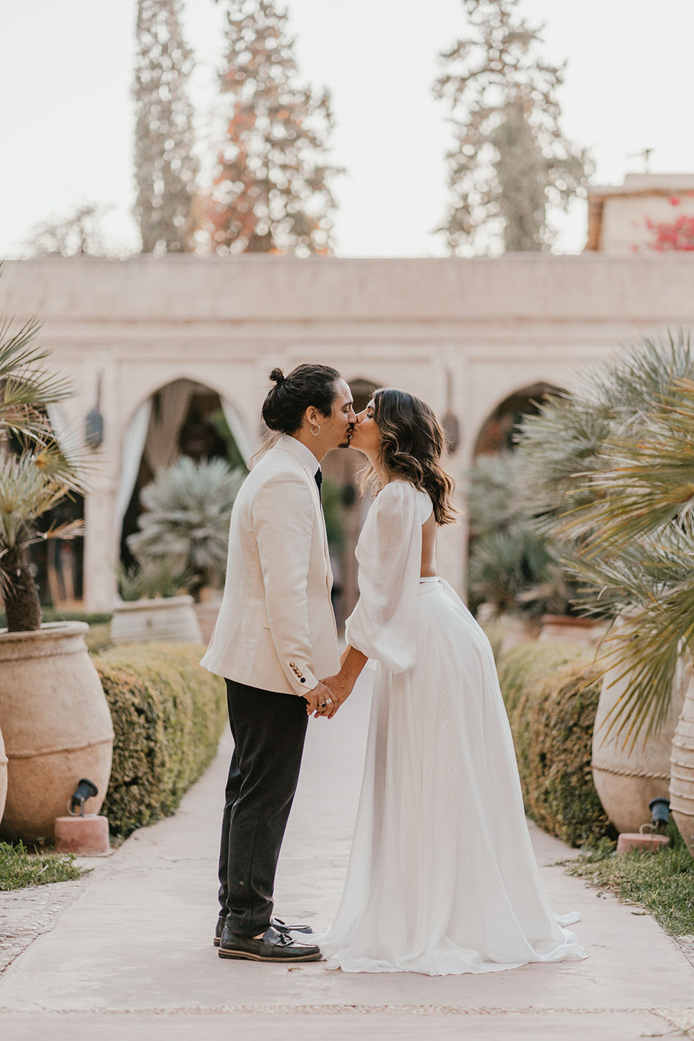 bride and groom kiss in the gardens at beldi country club wedding venue in morocco