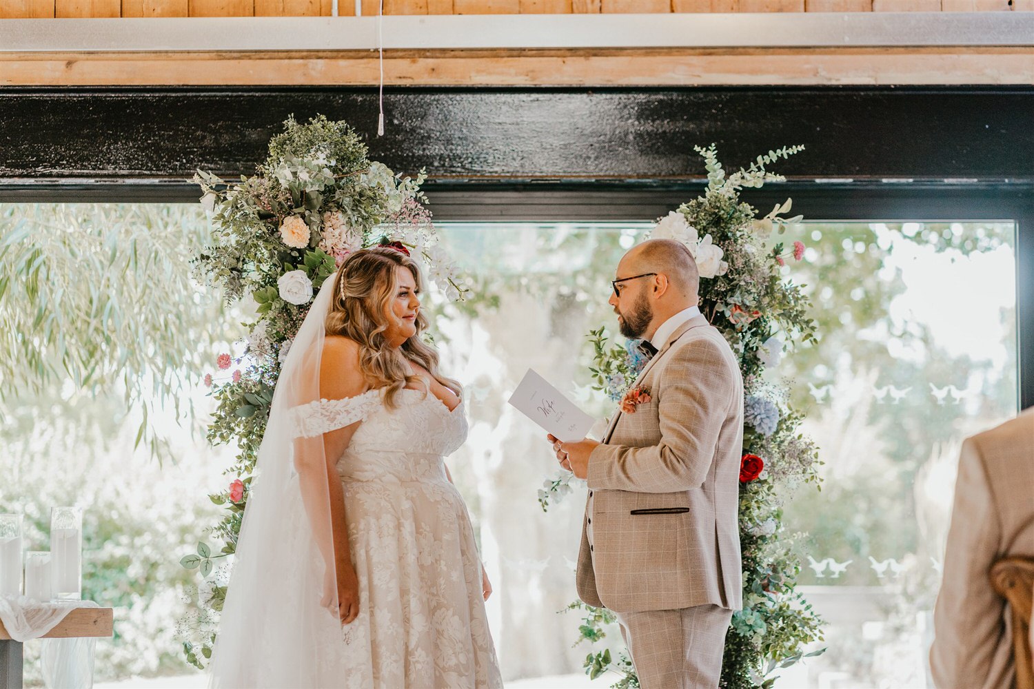 groom reads his vows as bride looks at him at indoor ceremony at chapel house estate in kent