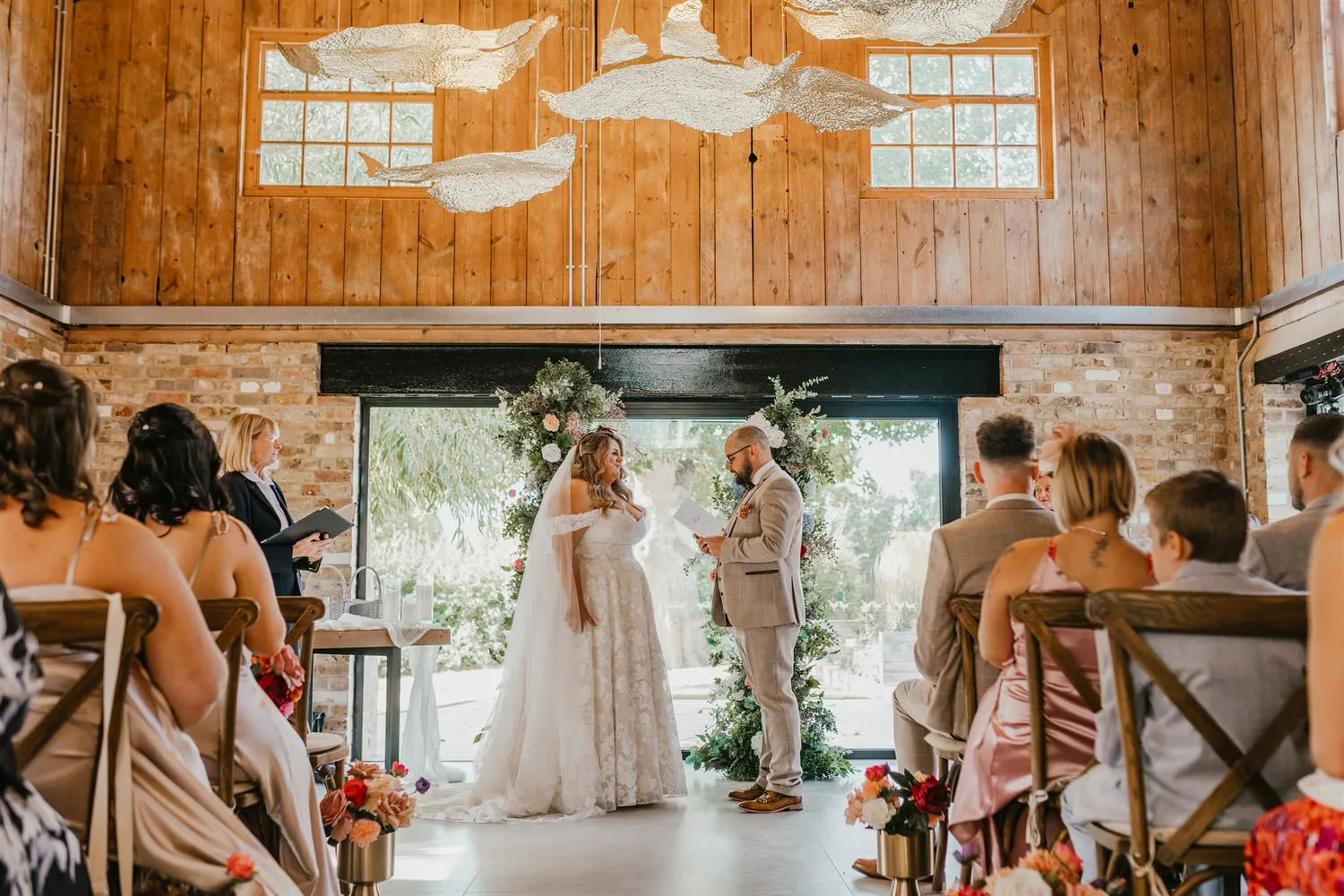 groom reads his vows as bride looks at him at indoor ceremony at chapel house estate in kent