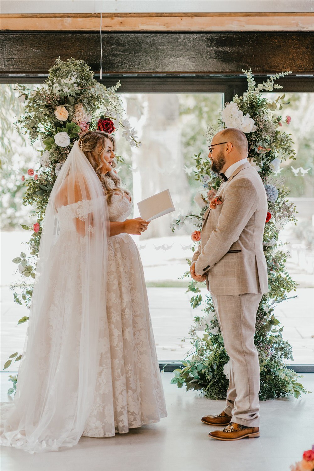 bride reads her vows as groom looks at him at indoor ceremony at chapel house estate in kent