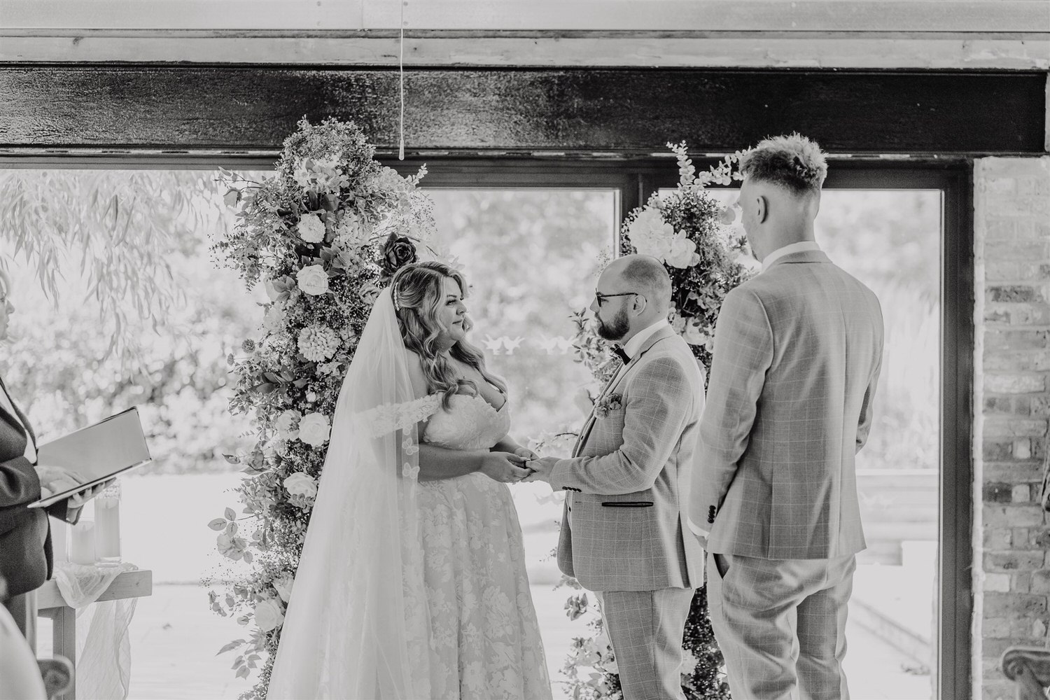 black and white photo as bride and groom exchange rings at chapel house estate wedding in kent