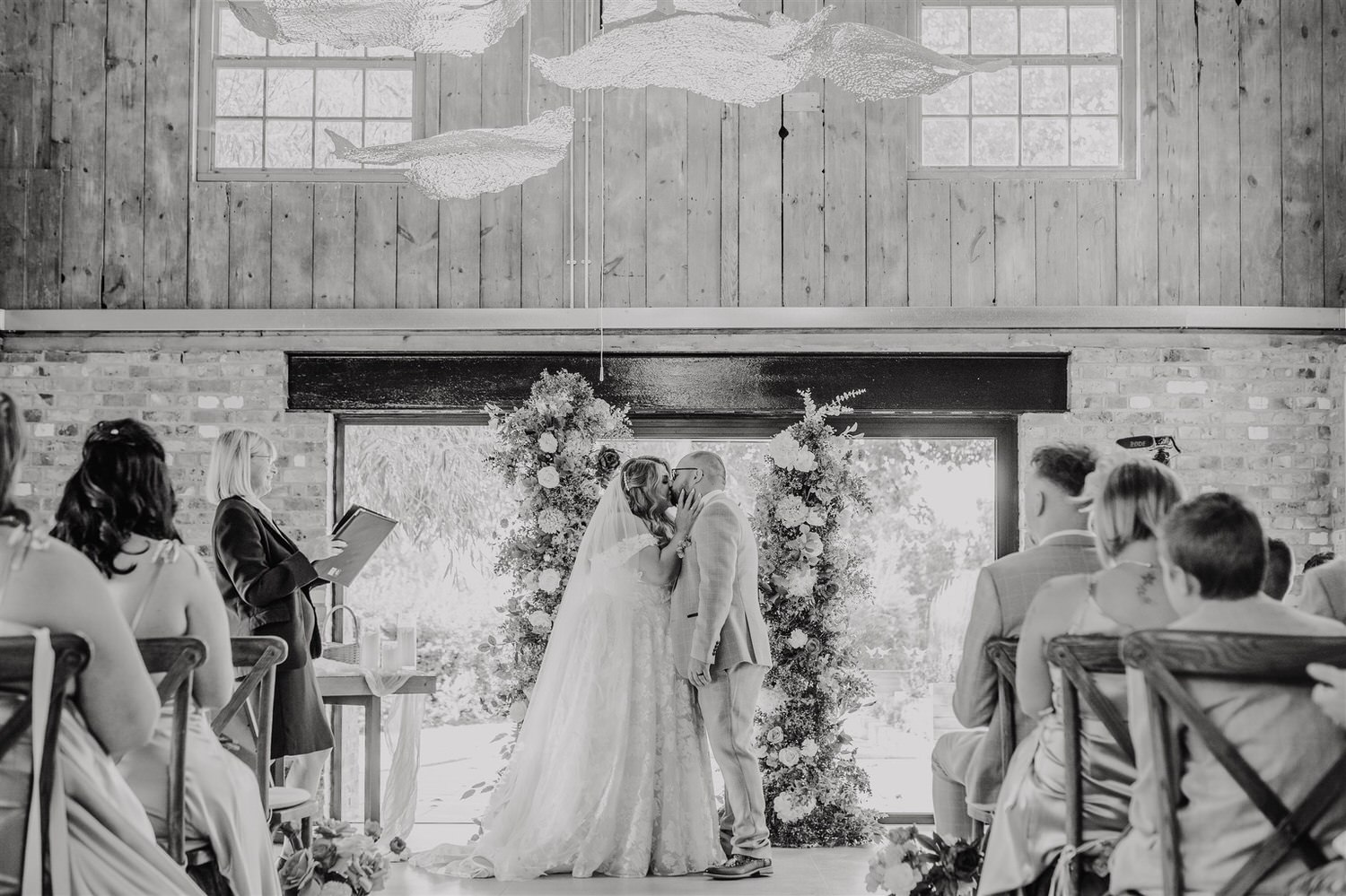black and white photo of bride and groom first kiss at chapel house estate wedding in kent