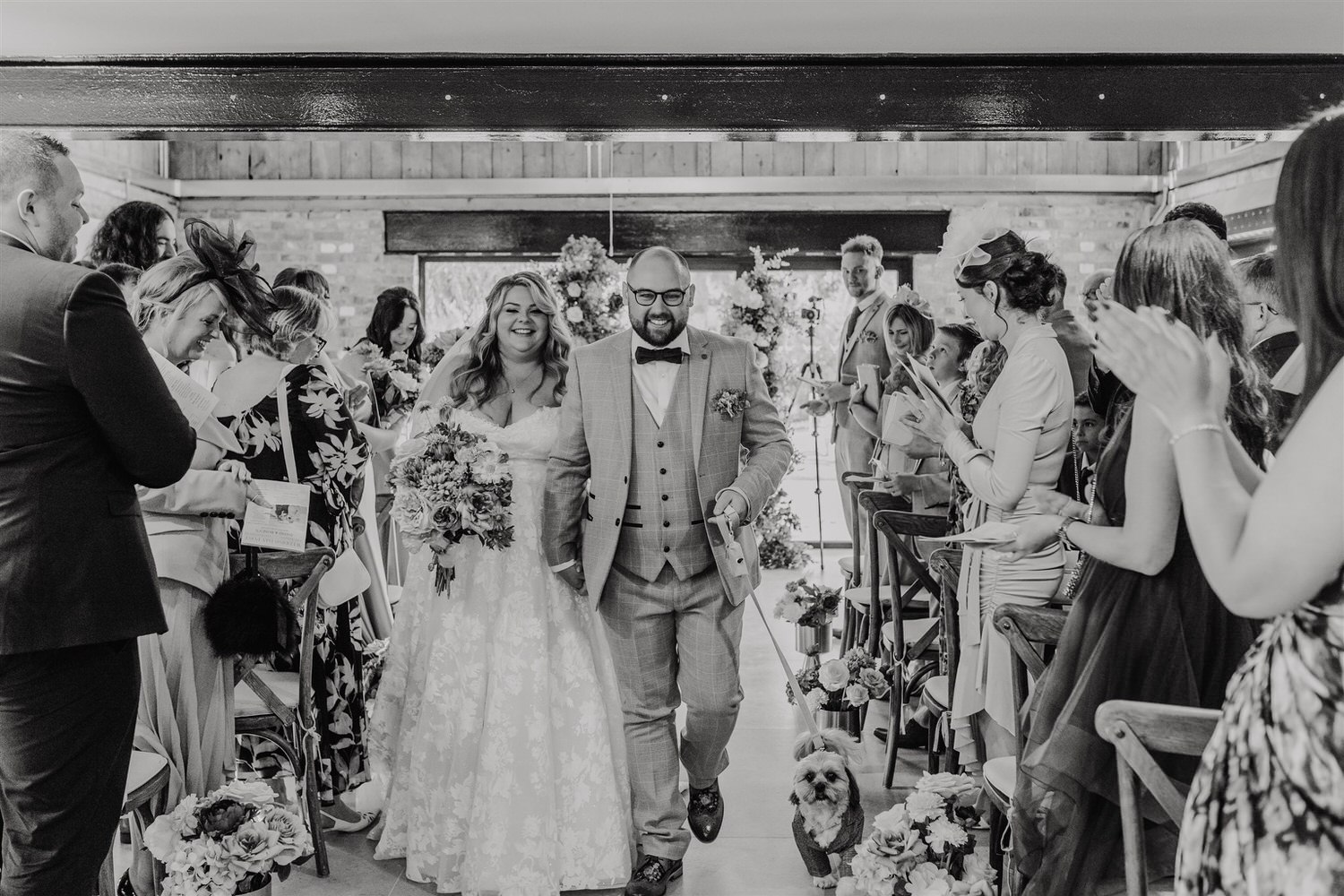 black and white photo as bride and groom walk back up the aisle after wedding ceremony at chapel house estate wedding venue in kent