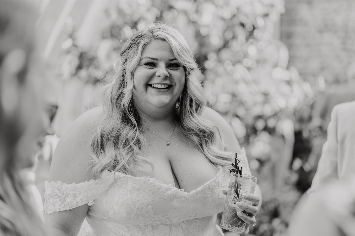 black and white photo of bride during drinks reception in the courtyard at chapel house estate wedding venue in kent