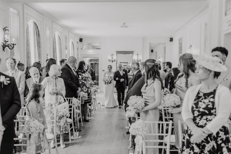 black and white photo of bride walking down the aisle with her father at hotel du vin wedding ceremony