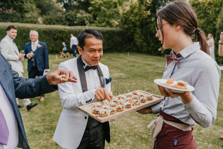 guest eating canapés during drinks reception in the gardens at hotel du vin tunbridge wells wedding