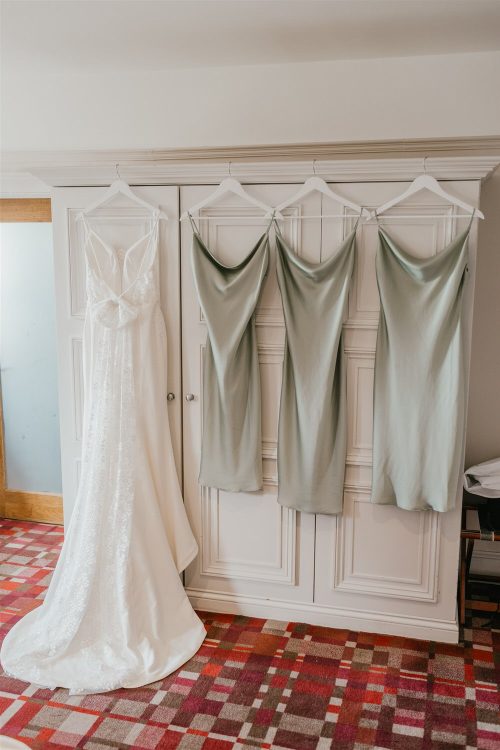 bride and bridesmaid dresses hung on wardrobe