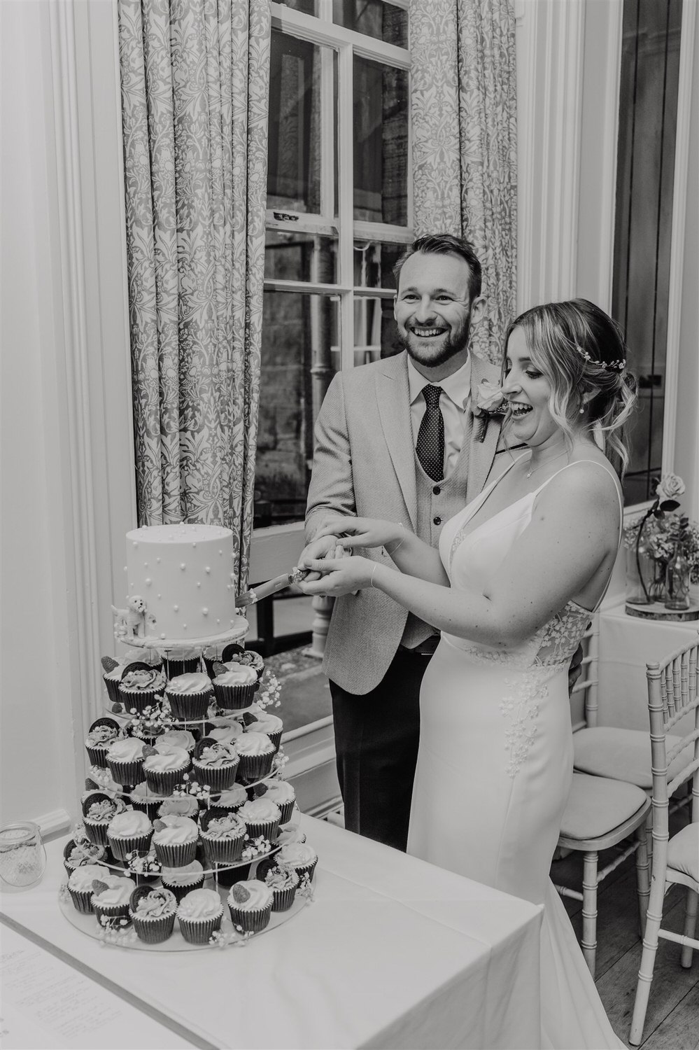 black and white photo of bride and groom cutting cake in ballroom at hotel du vin tunbridge wells