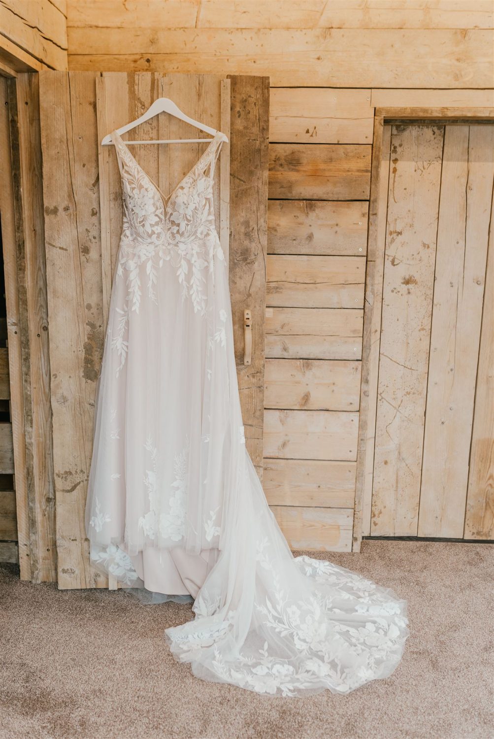 bride's tulle and lace wedding dress hung on a wooden door
