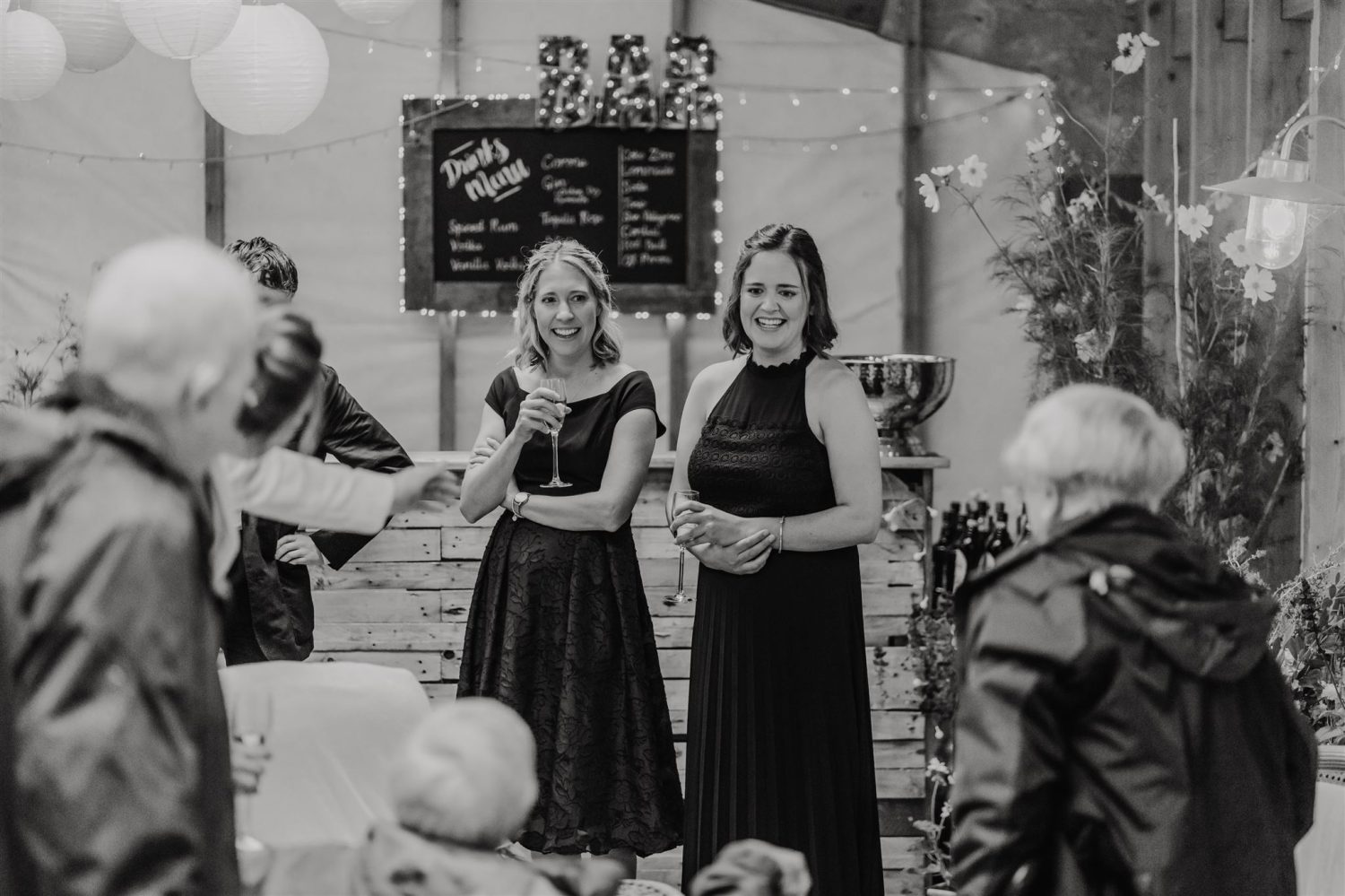 black and white photo of bridesmaids chatting with other guests at acorn barn wedding
