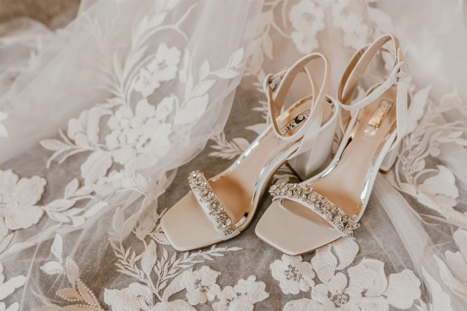 bride's shoes sitting on the lace train of her wedding dress