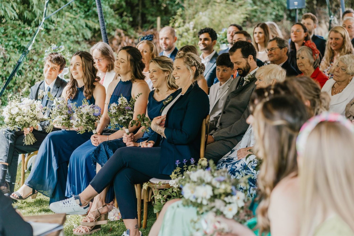 wedding guests smile during outdoor wedding ceremony at acorn barn