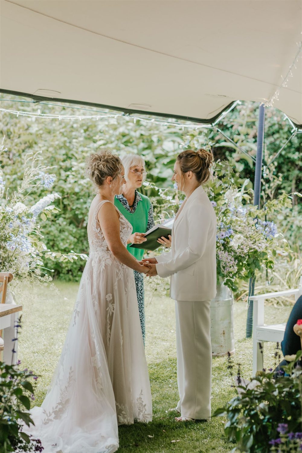 brides hold hands during outdoor wedding ceremony at acorn barn wedding venue in oxfordshire