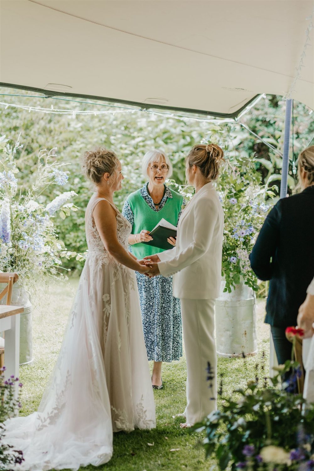 brides hold hands during outdoor wedding ceremony at acorn barn wedding venue in oxfordshire