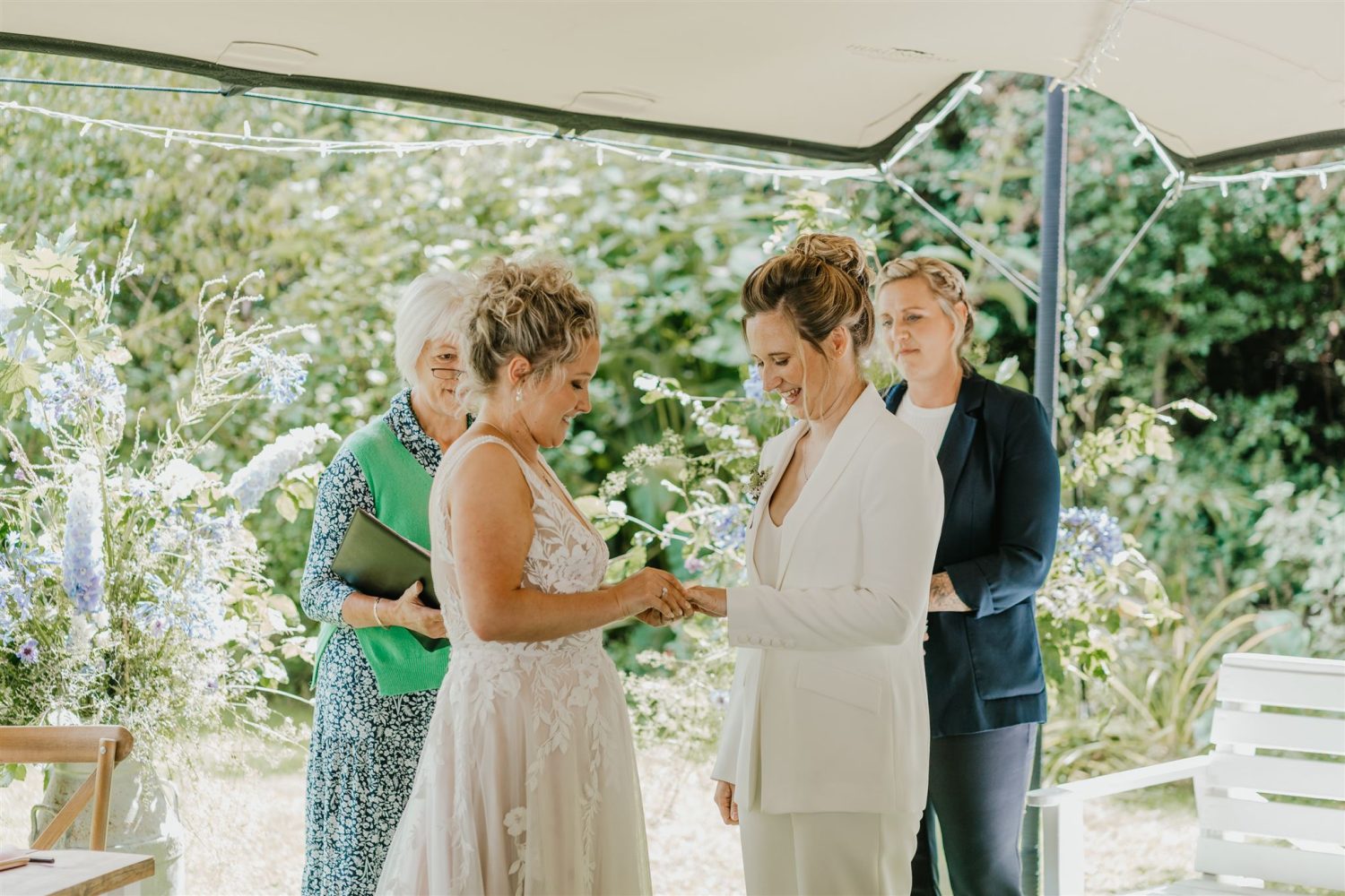 brides exchange rings during garden ceremony at acorn barn wedding venue in oxfordshire