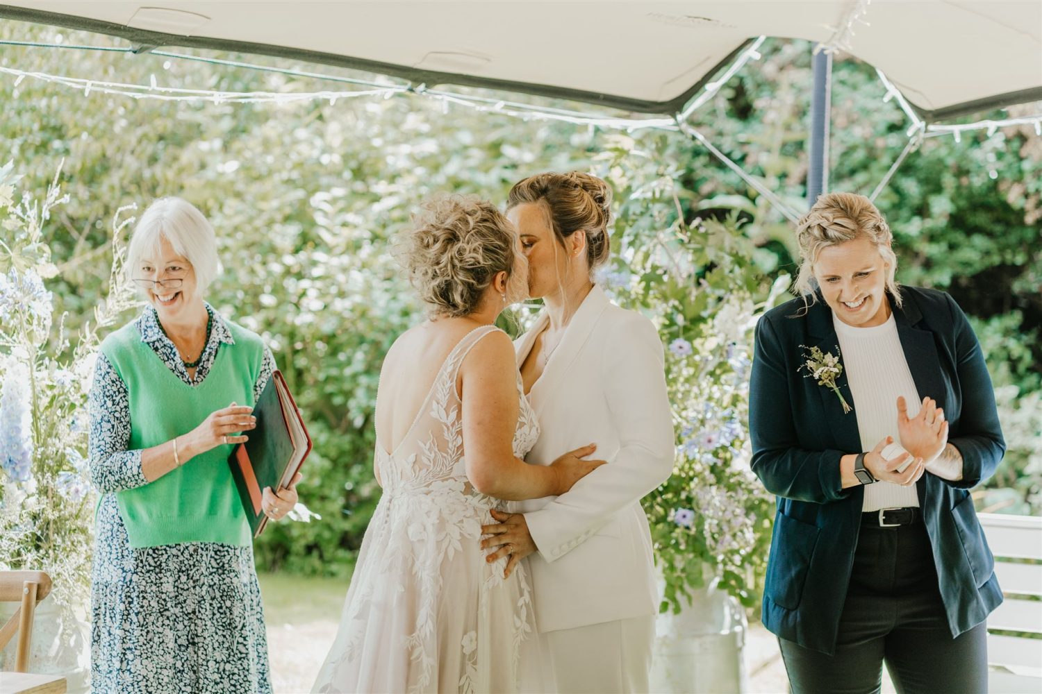 brides share first kiss during garden wedding ceremony at acorn barn wedding venue in oxfordshire