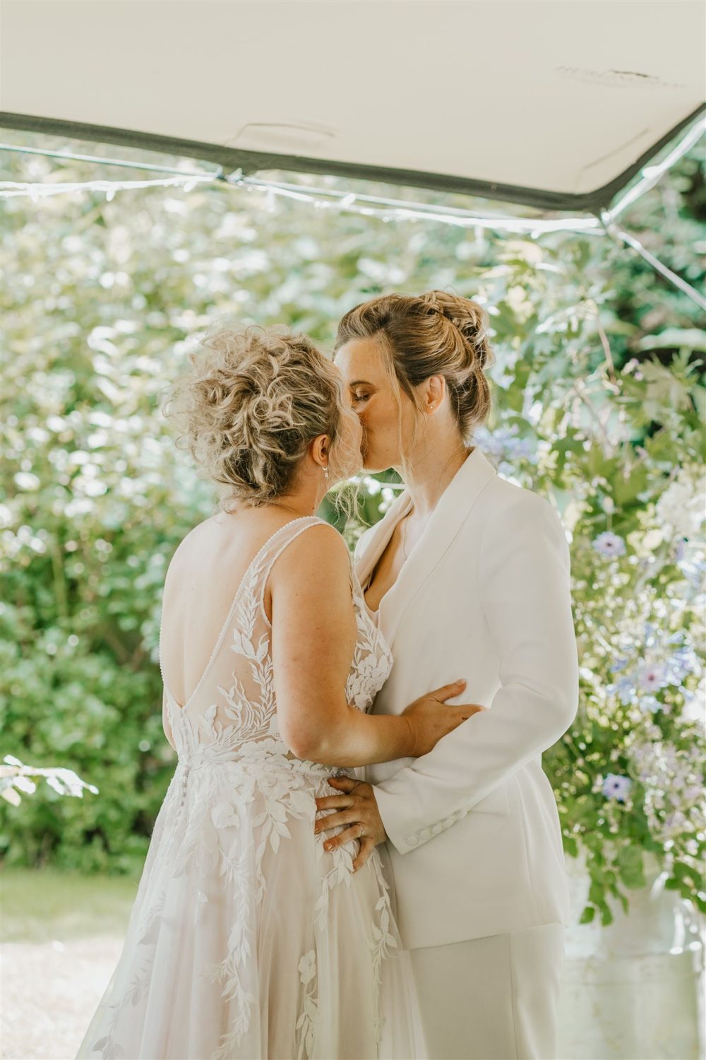 brides share first kiss during garden wedding ceremony at acorn barn wedding venue in oxfordshire