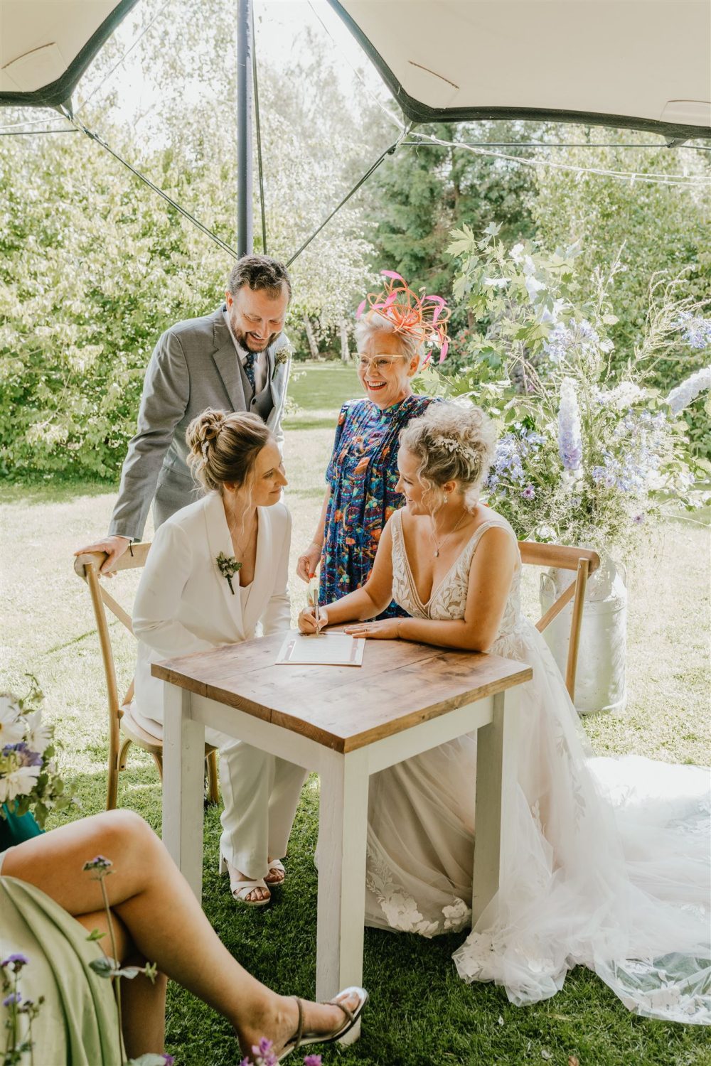 brides sign their wedding certificate after garden wedding ceremony at acorn barn in oxfordshire