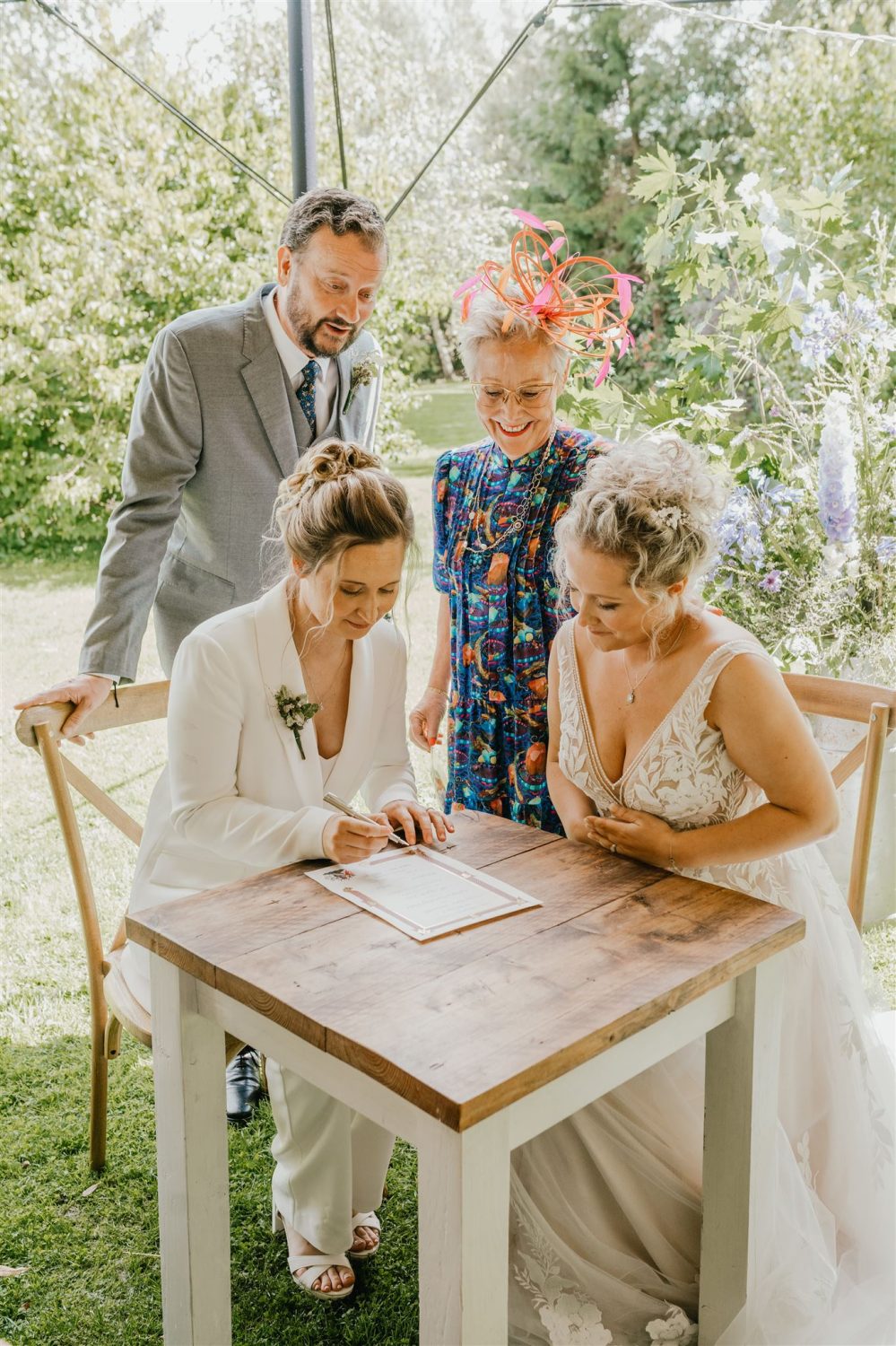 brides sign their wedding certificate after garden wedding ceremony at acorn barn in oxfordshire