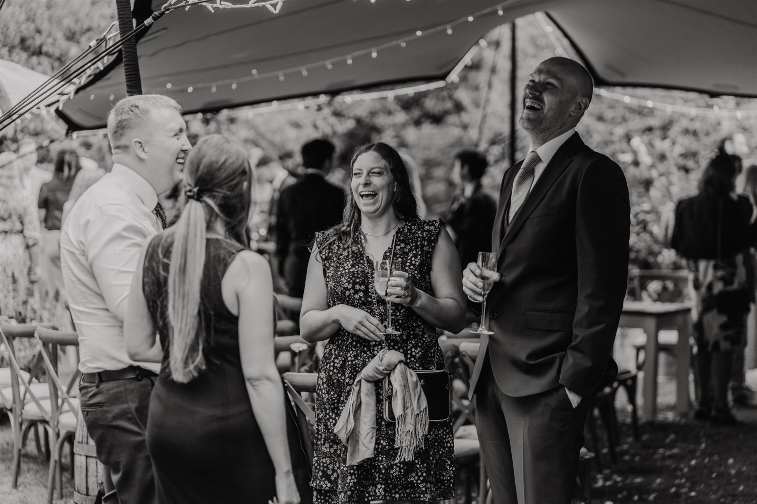 black and white photo of wedding guests laughing during wedding drinks reception