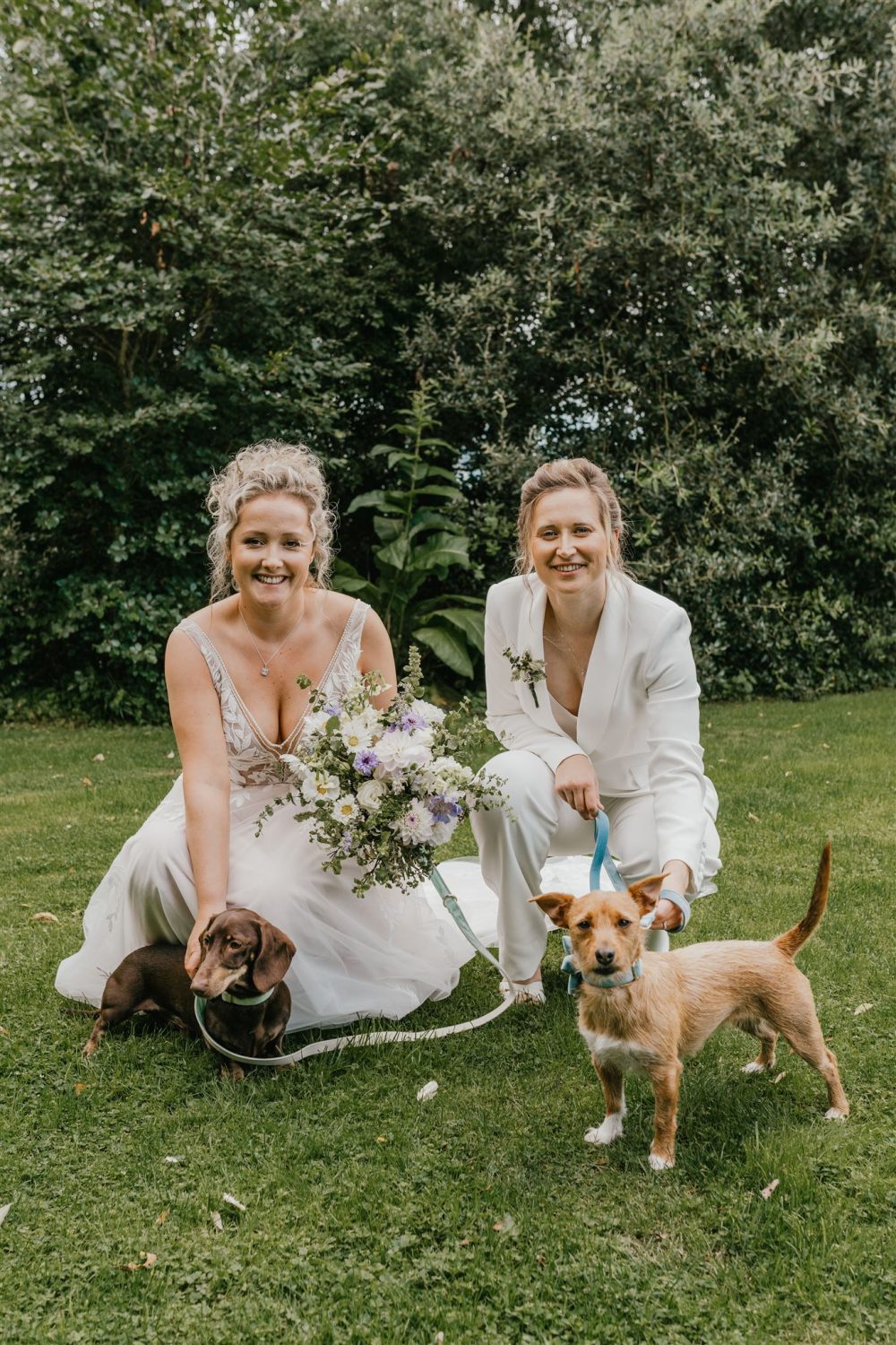 brides pose whilst holding their dogs at their oxfordshire wedding