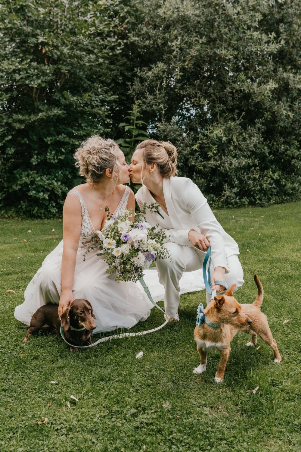 brides kiss whilst holding their dogs at their oxfordshire wedding