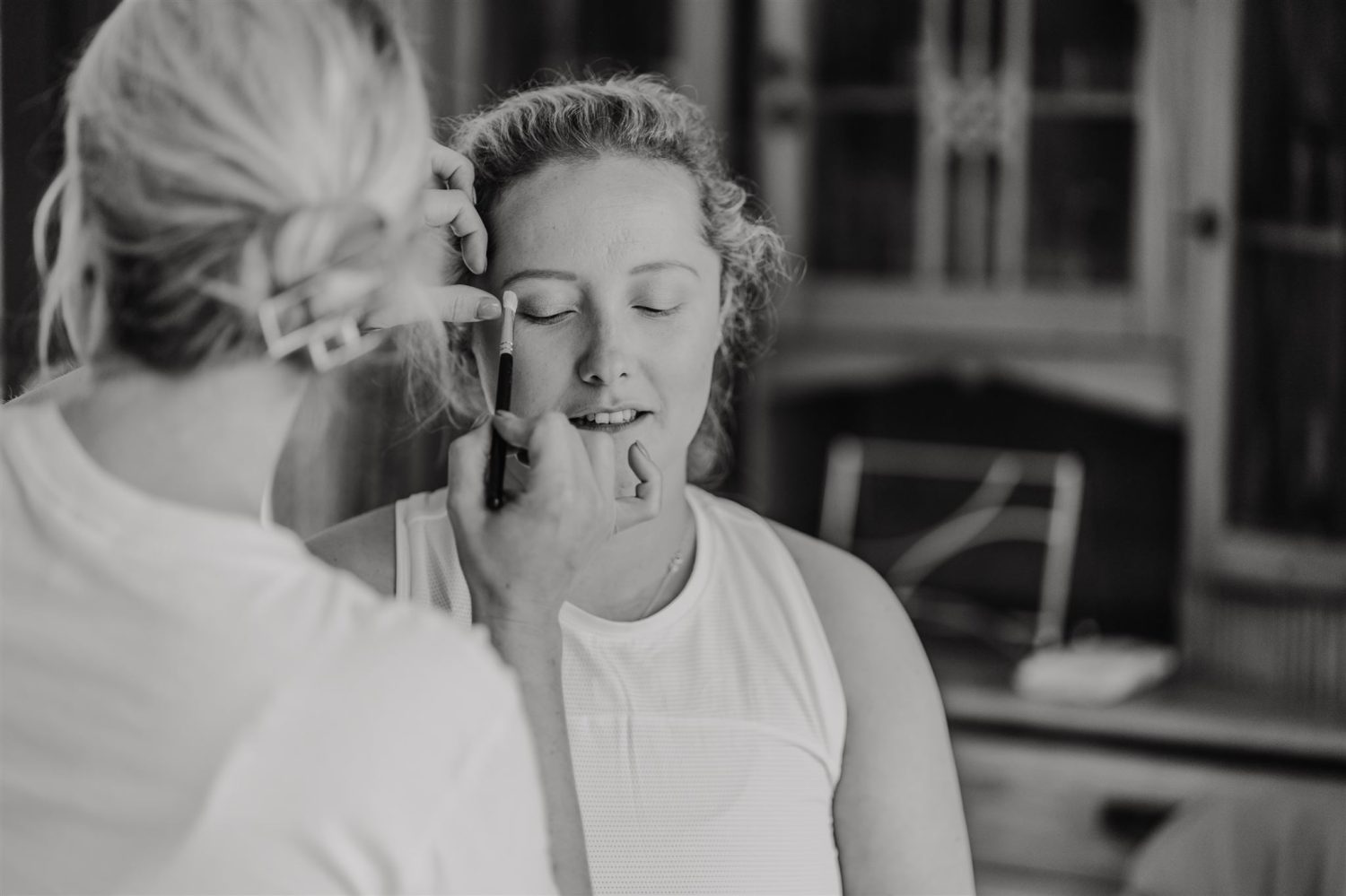 black and white photo of bride getting her makeup done on her wedding morning