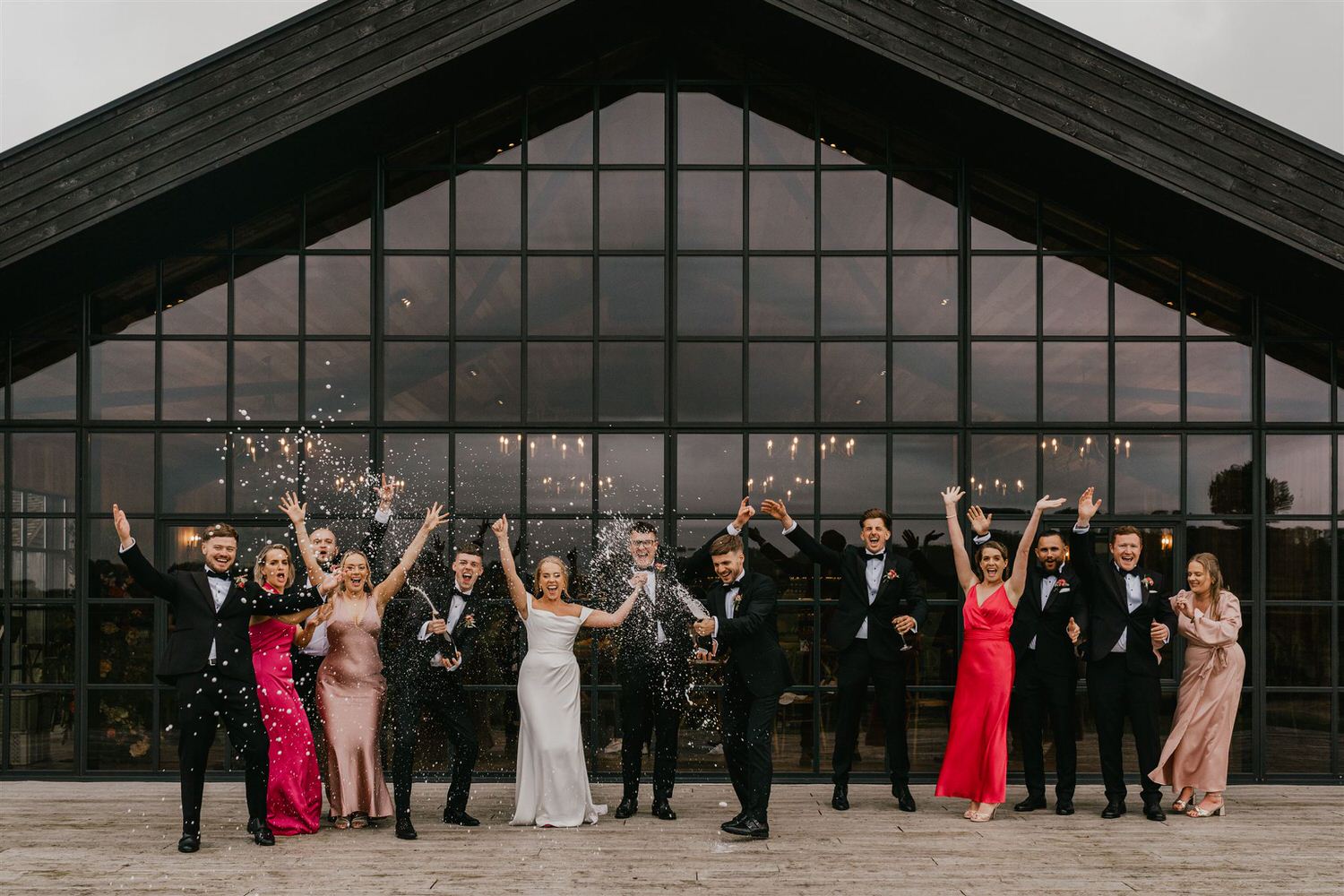 bride and groom champagne spray with bridal party outside of botley hill barn