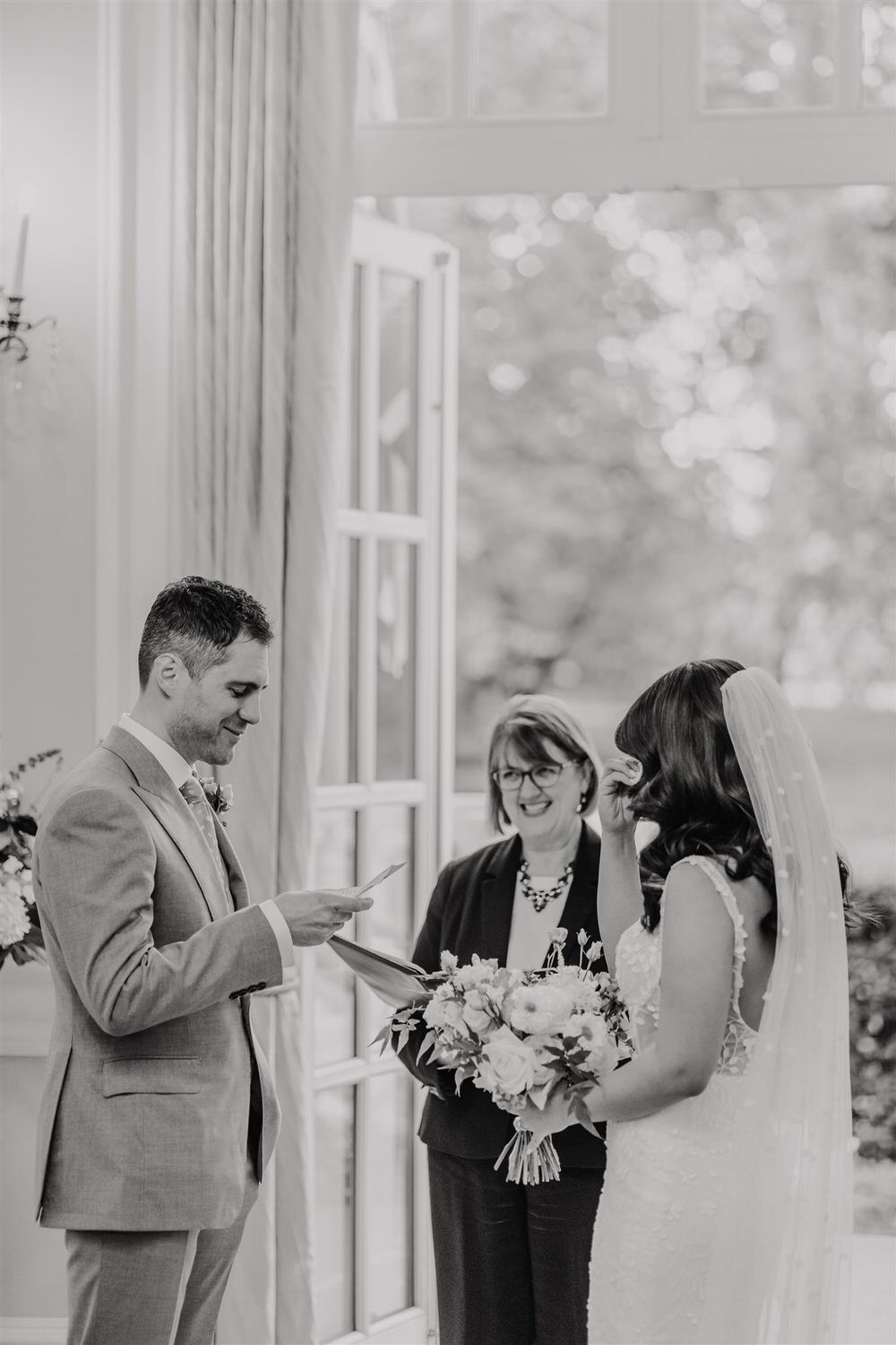 black and white photo of groom reading vows during wedding ceremony in the loggia at mandarin oriental hyde park luxury wedding venue in london