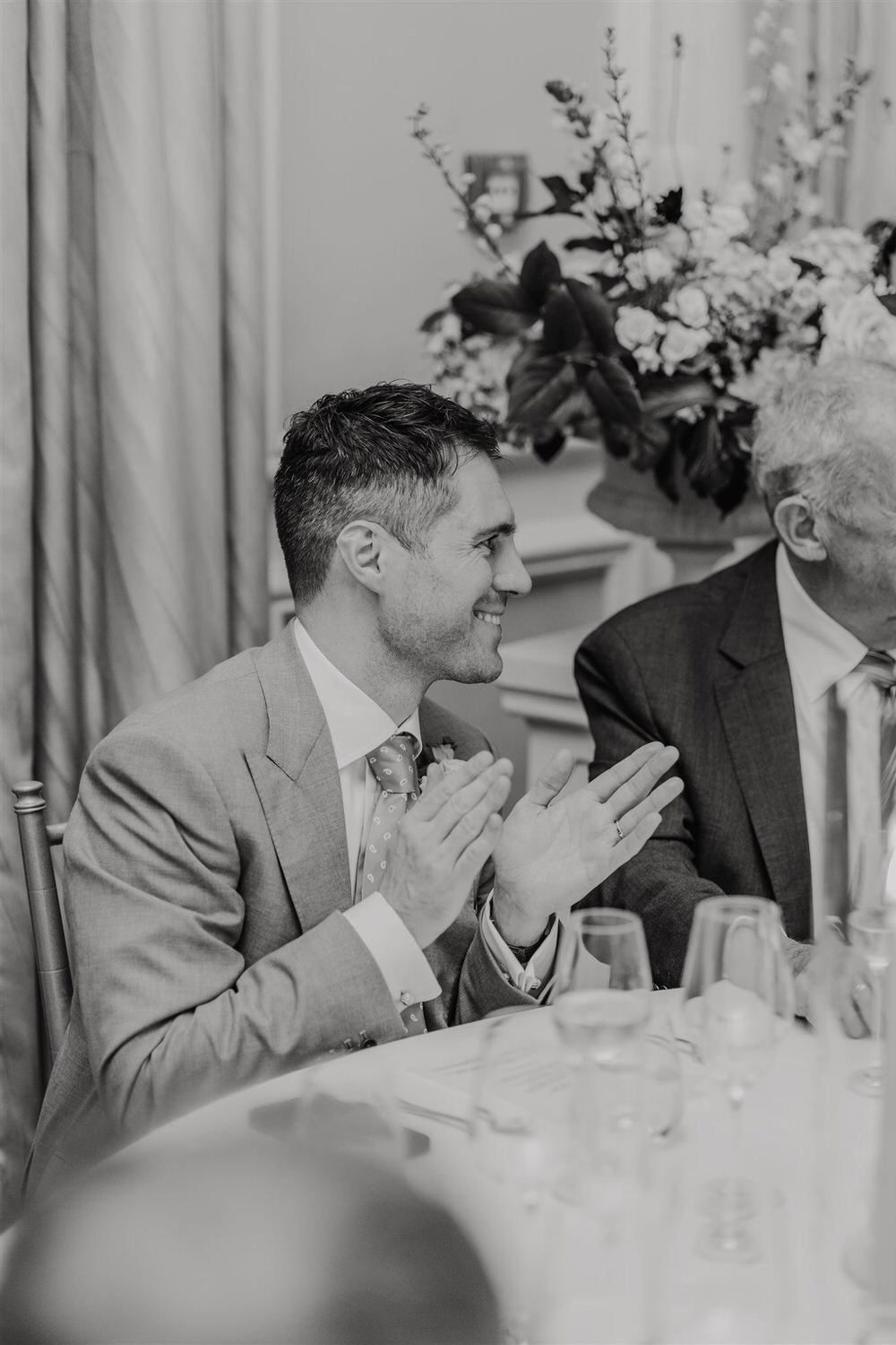 black and white photo of groom clapping during wedding speech