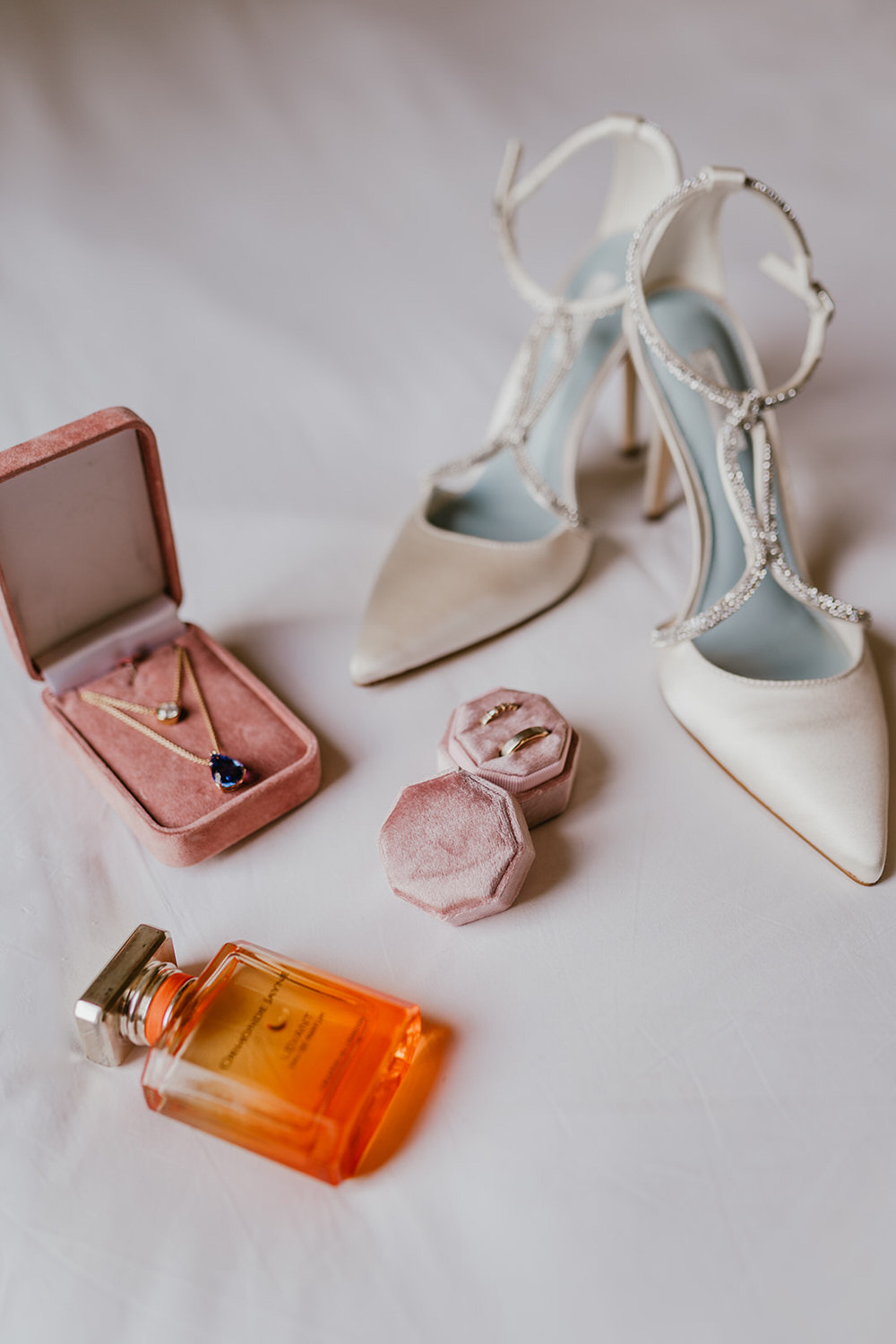 bridal shoes, jewellery and perfume sitting on the bed in morden hall bridal prep suite