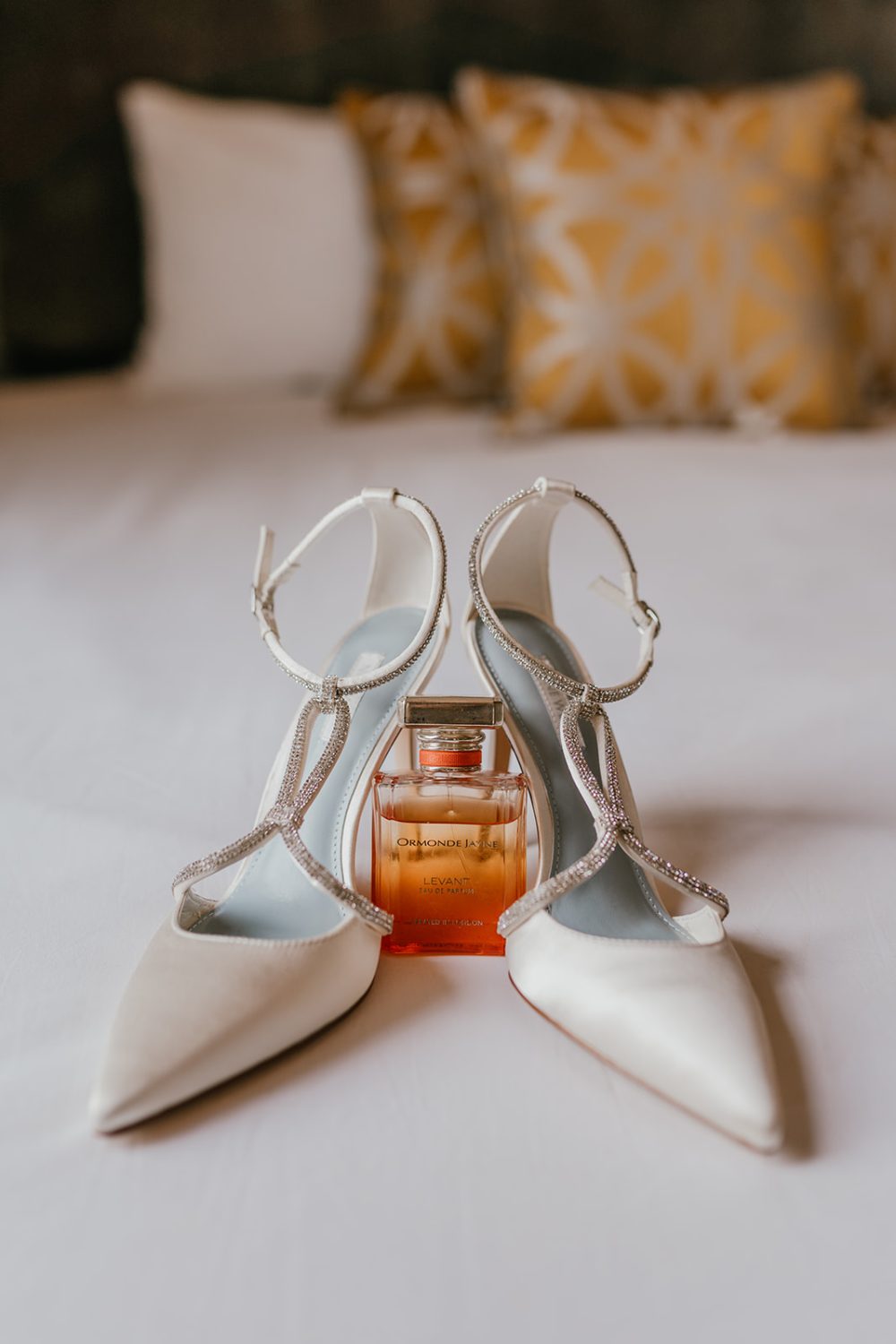 bridal shoes and perfume sitting on the bed in morden hall bridal prep suite
