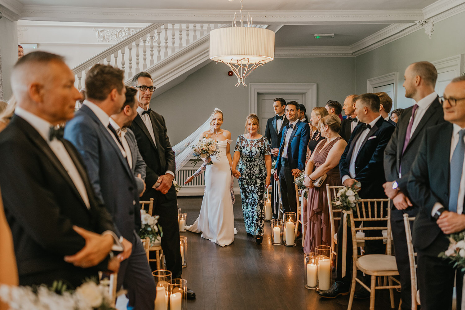 bride walks down the aisle with her mum at wedding ceremony at morden hall in london