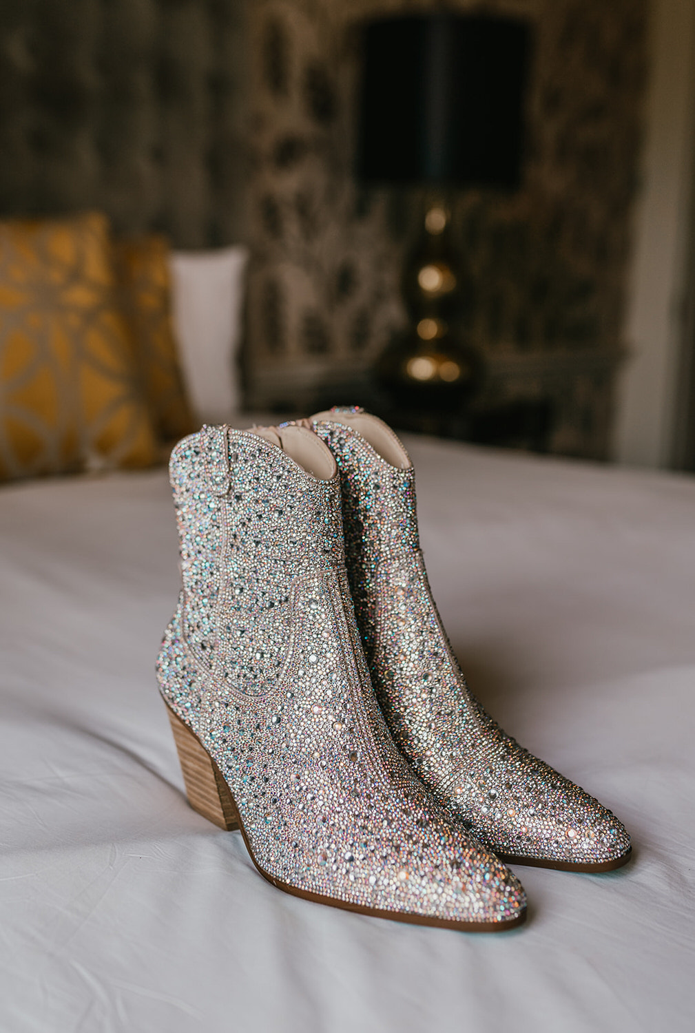 sparkly cowgirl boots sitting on the bed in morden hall bridal prep suite