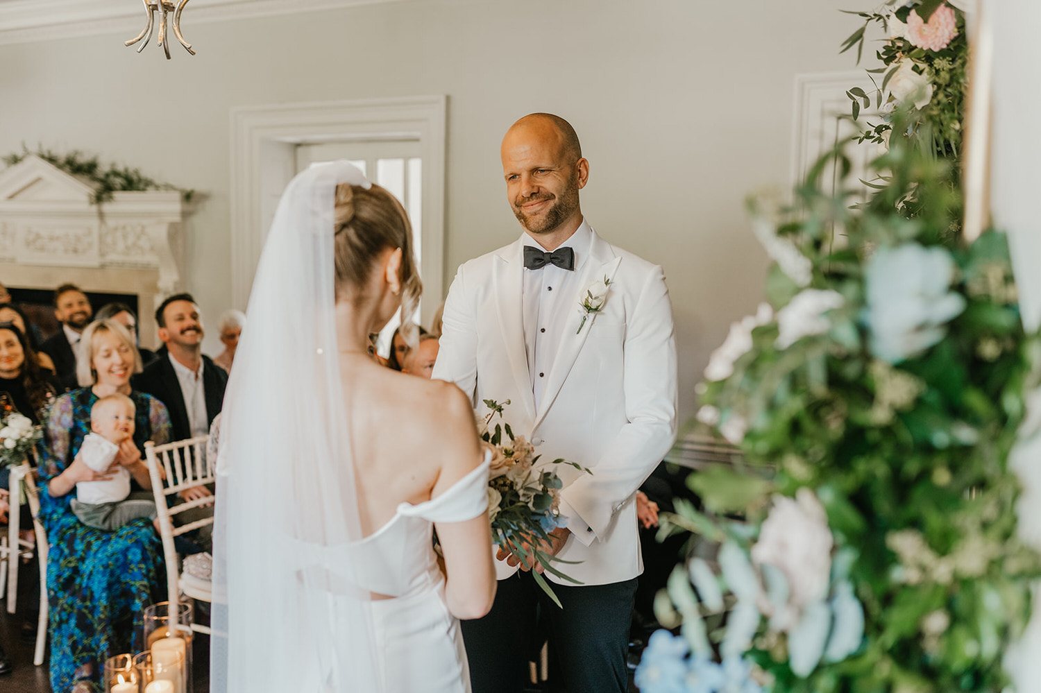 groom smiles at bride during wedding ceremony at morden hall in london