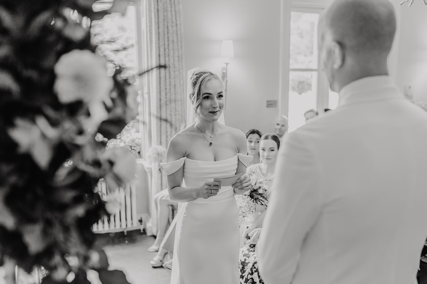 black and white photo of bride reading vows during wedding ceremony at morden hall in london