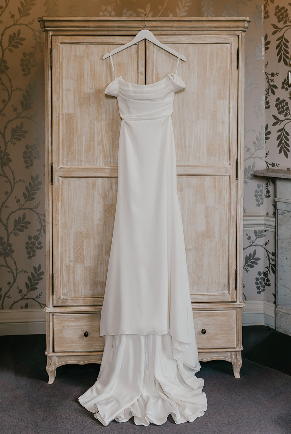 alena leena wedding dress hung on wardrobe in morden hall bridal prep suite