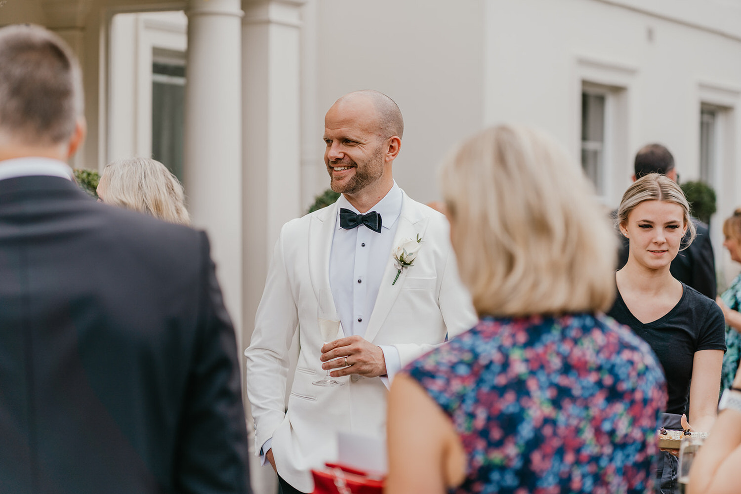 groom talks to guests during drinks reception at morden hall wedding